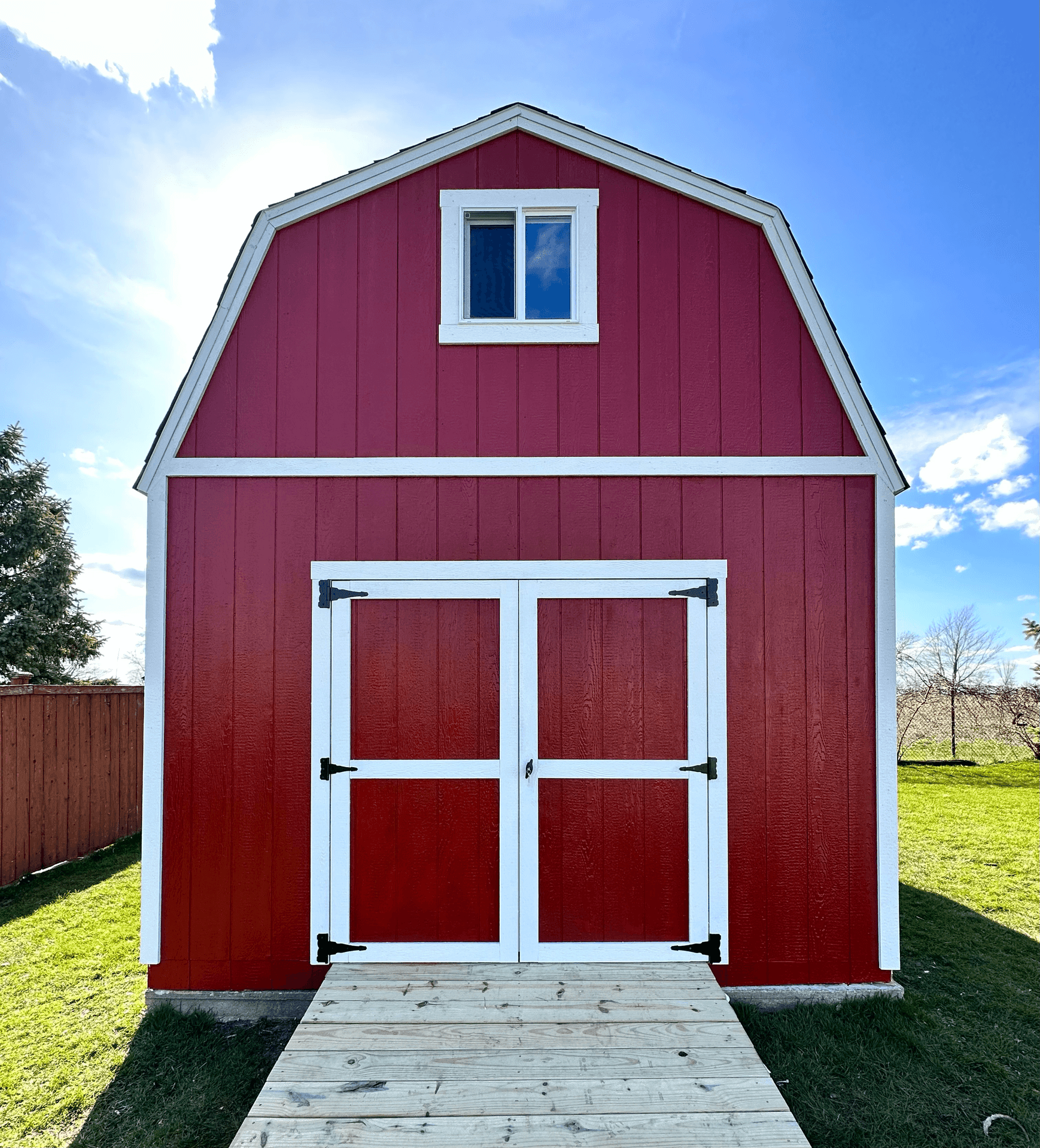 Front view of a red barn with white trim under a blue sky.